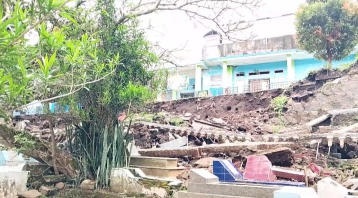 TPT TPU Dayeuhhandap Garut Ambruk, Puluhan Makam Tertimbun, Jalan Terancam Longsor Keterangan Foto: Kondisi Tembok Penahan Tanah (TPT) dan pagar Tempat Pemakaman Umum (TPU) di Jalan Dayeuhandap, Kelurahan Kota Kulon, Garut, yang ambruk akibat hujan deras disertai angin kencang, Jumat (3/4/2026). Material longsor terlihat menimbun puluhan makam dan berpotensi mengancam akses jalan raya di sekitar lokasi. Foto oleh : Indra R